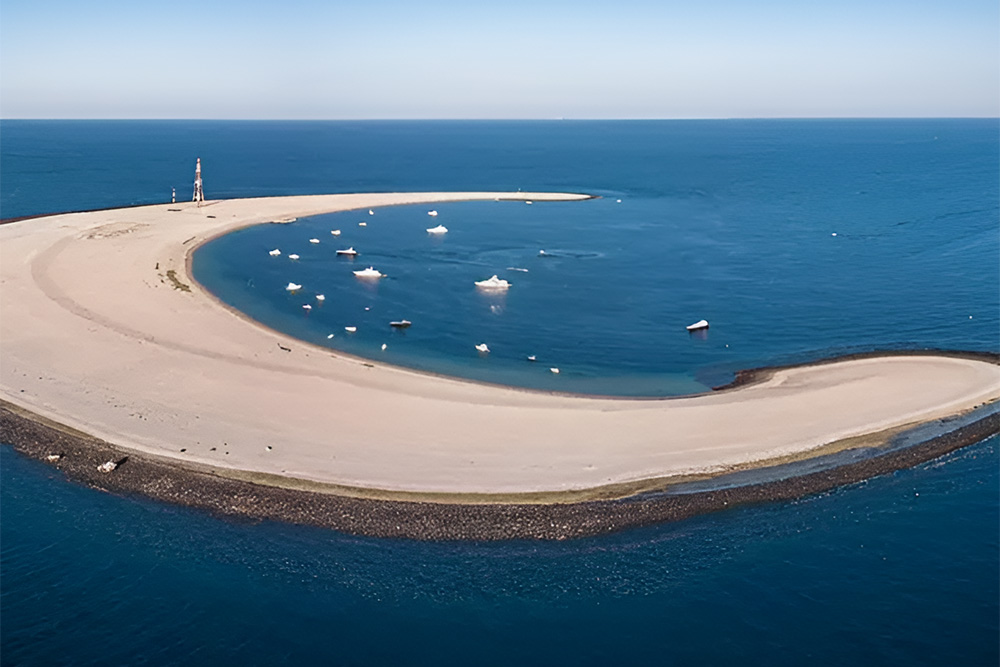 Sunset shot from a yacht, with Moon Island’s crescent behind a small beach camp.